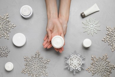 Photo of Woman with jar of hand cream at light grey table, top view