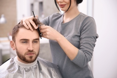 Photo of Professional female hairdresser working with client in salon