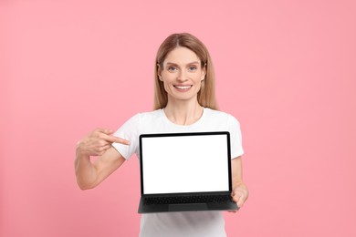 Photo of Happy woman showing laptop on pink background