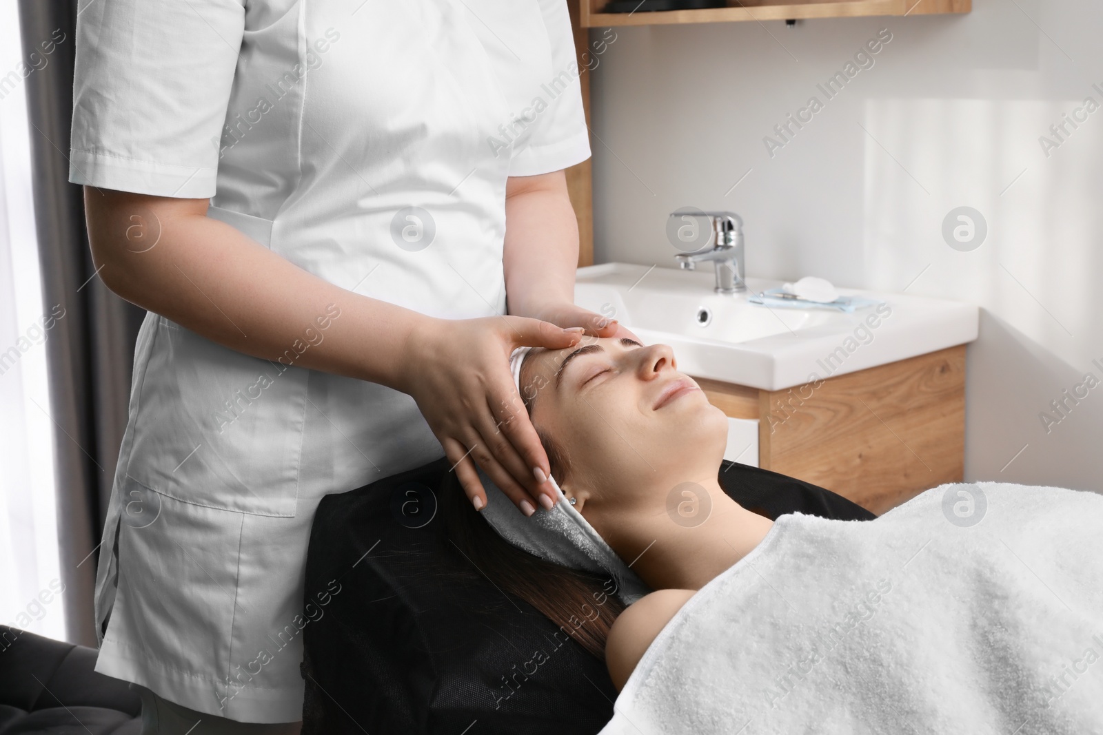 Photo of Cosmetologist making face massage to client in clinic, closeup