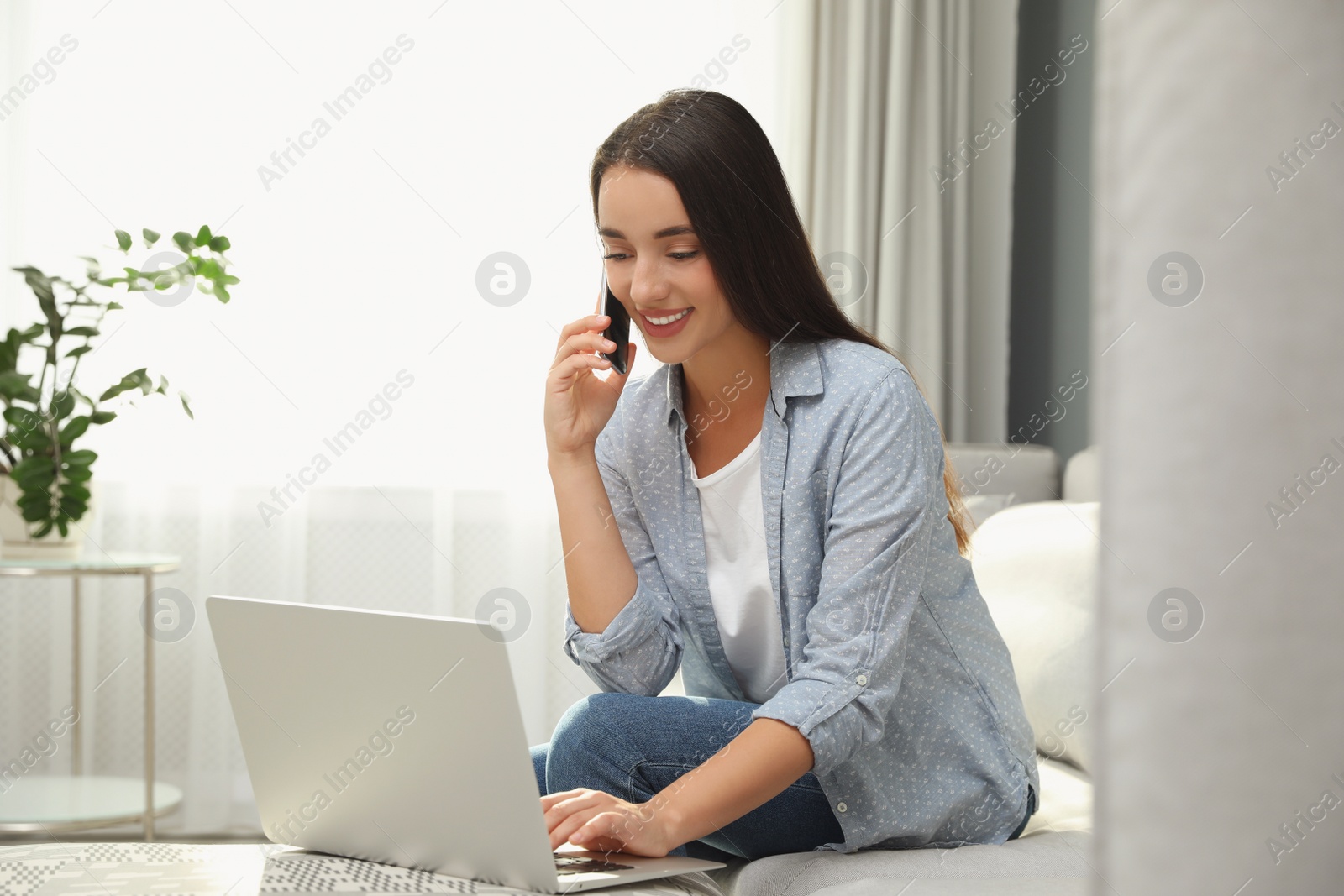 Photo of Woman with modern smartphone and laptop at home. Searching information