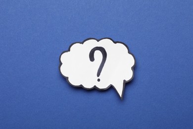 Paper speech bubble with question mark on blue background, top view