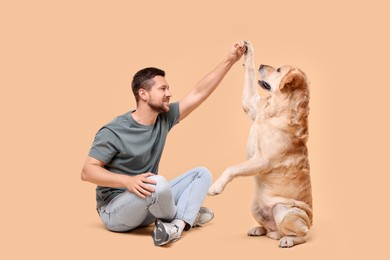 Man with adorable Labrador Retriever dog on beige background. Lovely pet