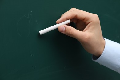 Photo of Teacher writing with chalk on green chalkboard, closeup. Space for text