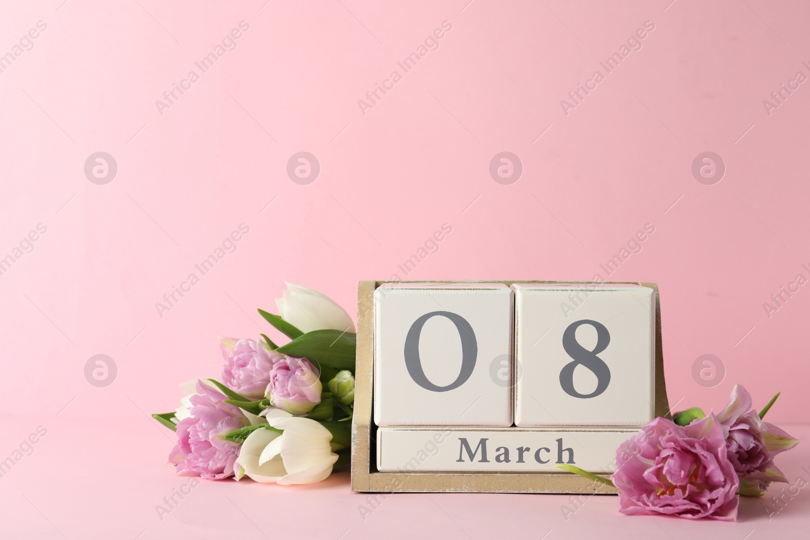 Photo of Wooden block calendar with date 8th of March and tulips on pink background, space for text. International Women's Day