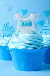 Photo of Beautifully decorated baby shower cupcakes for boy with cream and toppers on light blue background