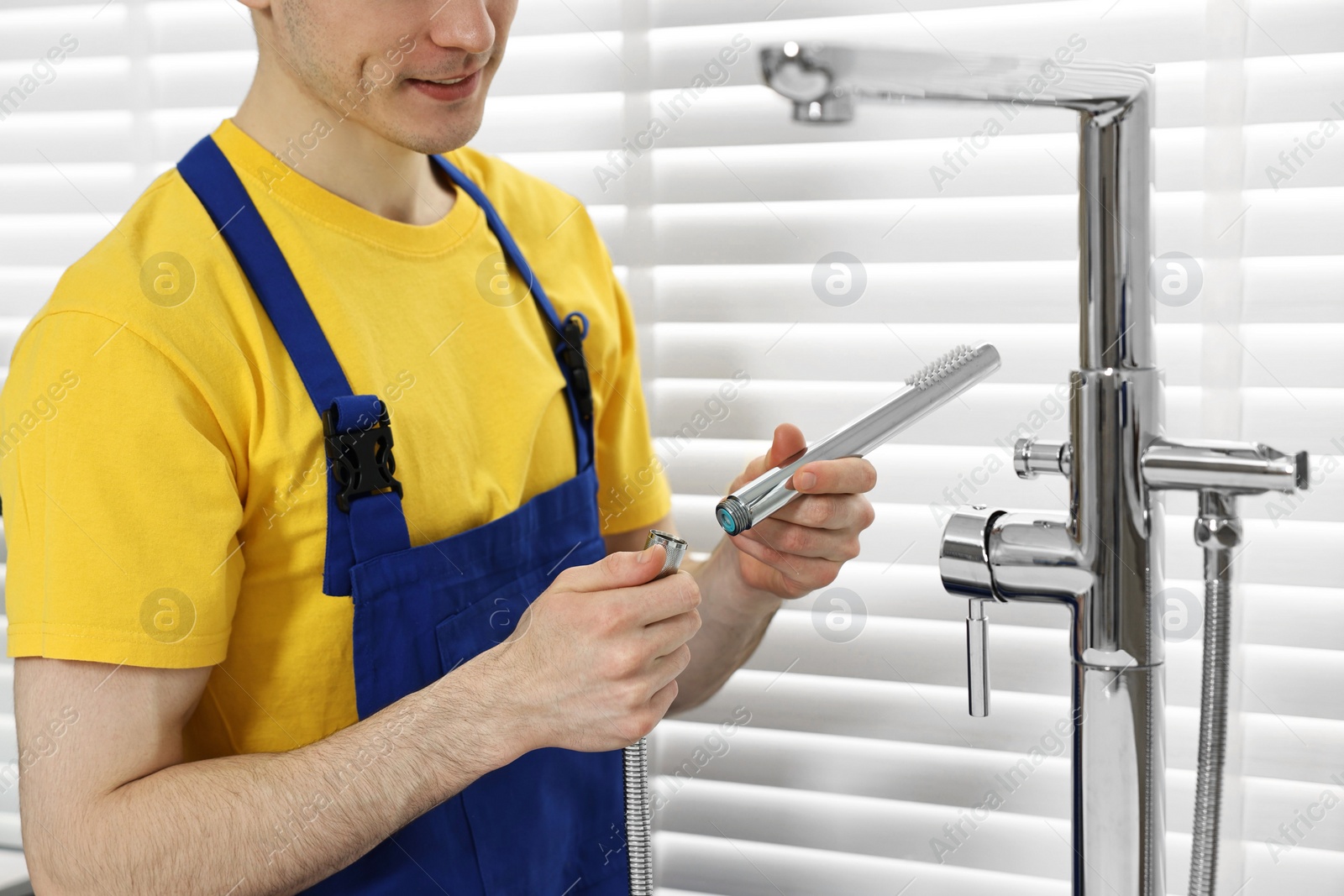 Photo of Plumber repairing metal faucet in bathroom, closeup