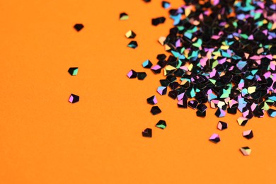Photo of Pile of shiny glitter on orange background, closeup. Space for text
