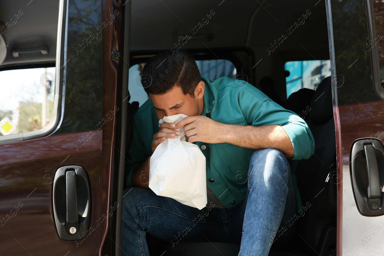 Photo of Man with paper bag suffering from nausea in car