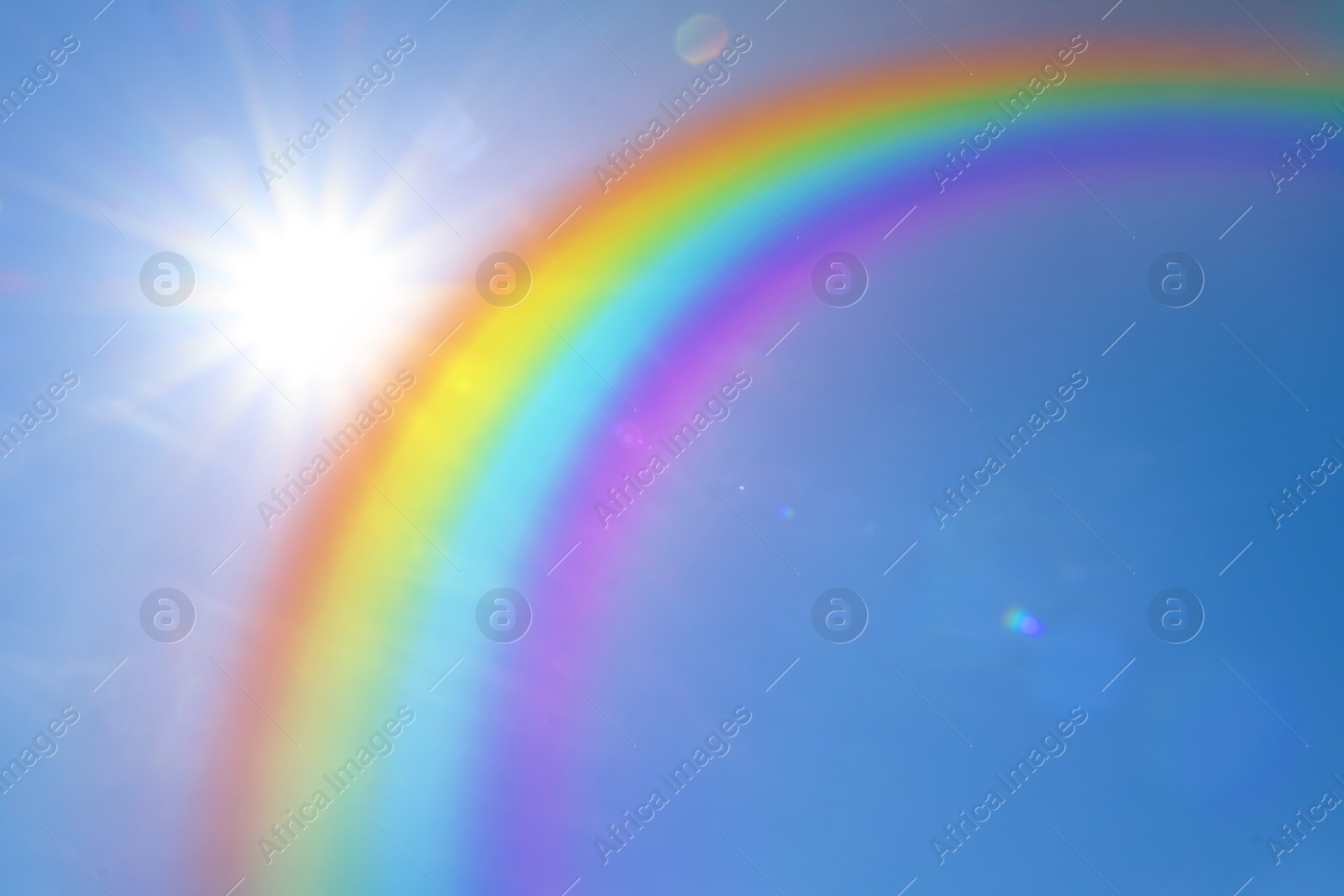 Image of Beautiful view of bright rainbow in blue sky on sunny day