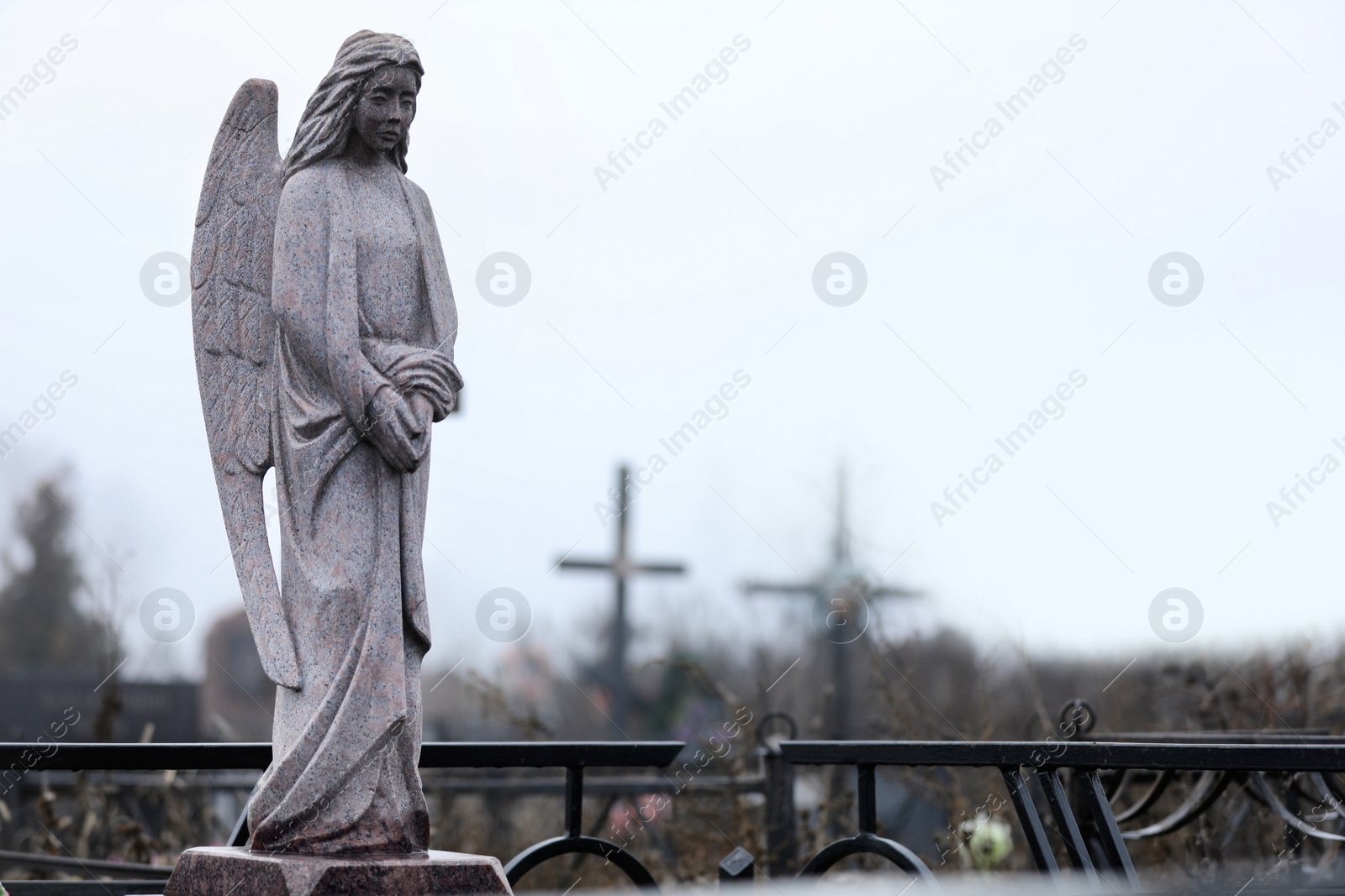 Photo of Grey granite angel on cemetery. Funeral ceremony