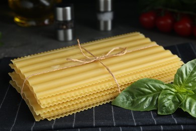 Uncooked lasagna sheets and basil on table, closeup