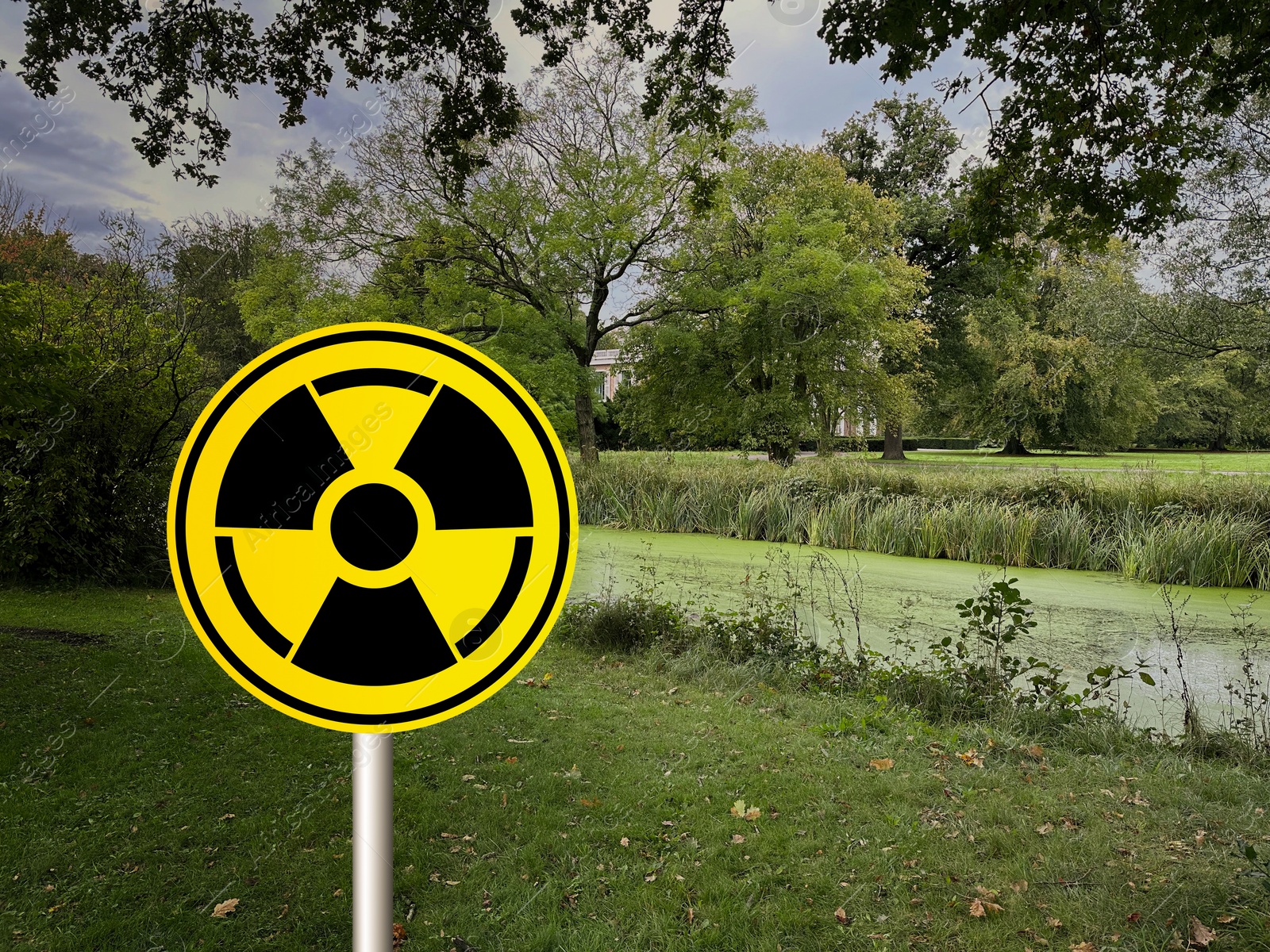 Image of Radioactive pollution. Yellow warning sign with hazard symbol in rural area