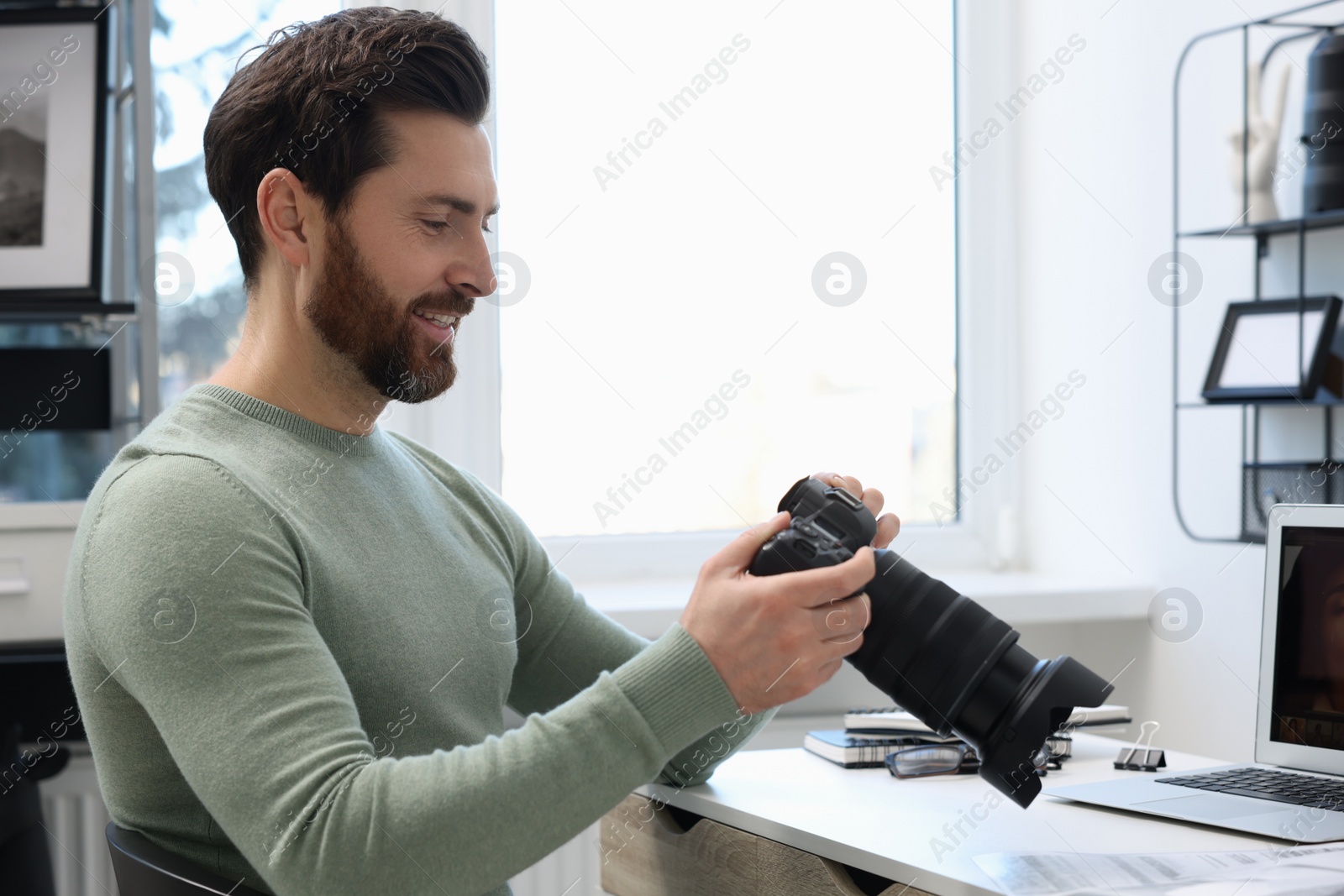 Photo of Professional photographer with digital camera at table in office