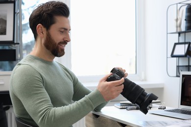 Photo of Professional photographer with digital camera at table in office