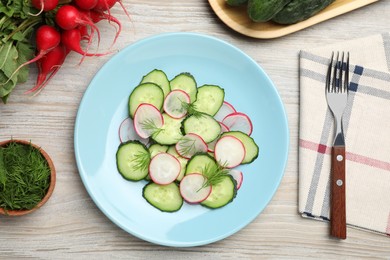 Photo of Tasty salad with cucumber and radish on wooden table, flat lay