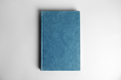 Hardcover book on light grey background, top view. Space for design