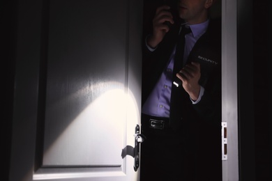 Male security guard with flashlight in dark room