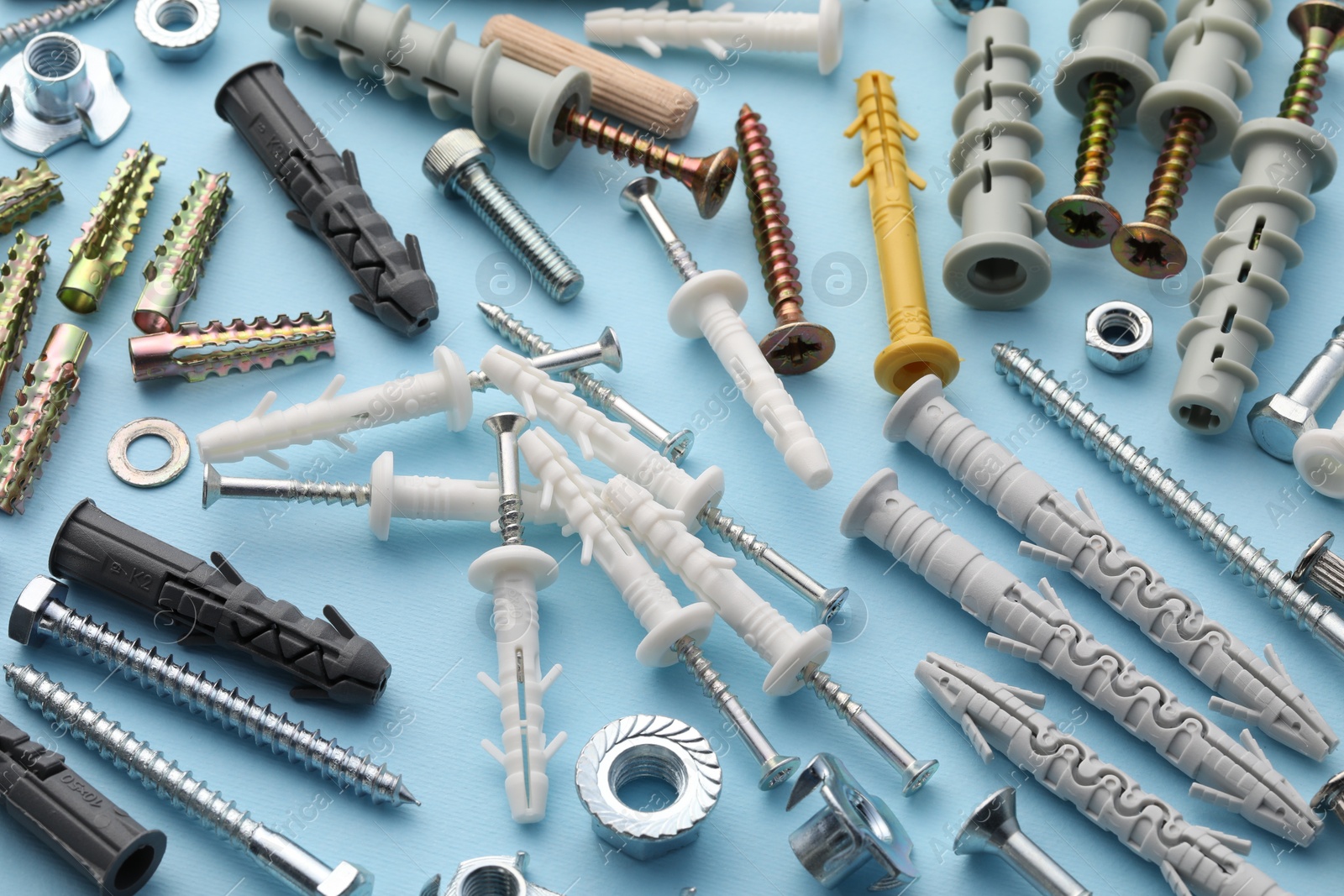 Photo of Many different fasteners and dowels on light blue background, above view