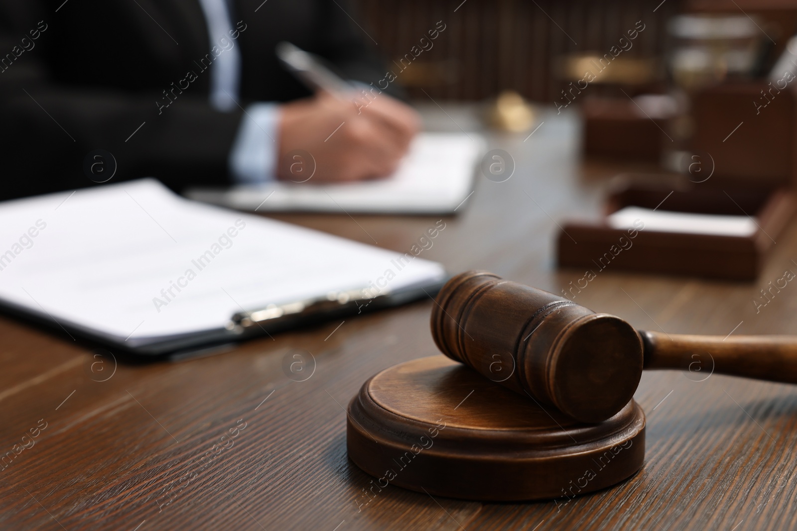 Photo of Lawyer working with documents at wooden table indoors, focus on gavel