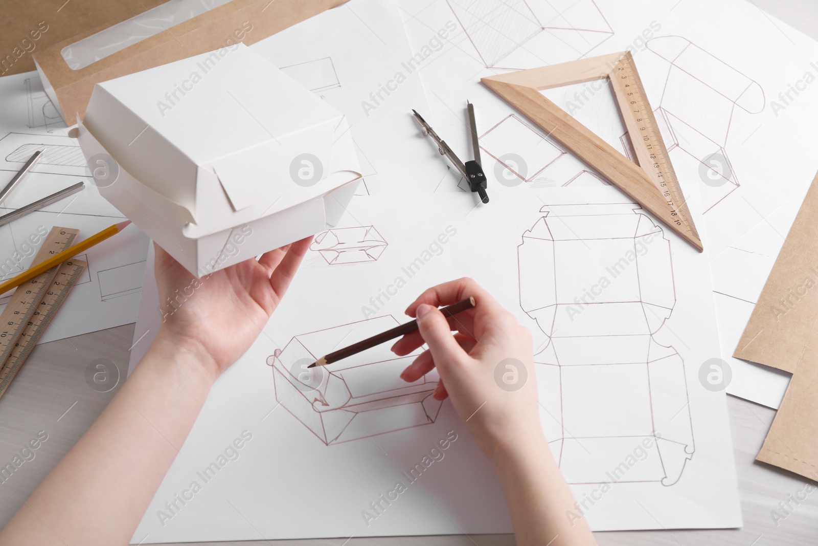 Photo of Woman creating packaging design at light wooden table, closeup