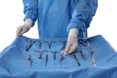 Photo of Doctor holding Pott's scissors near table with different surgical instruments on light background, closeup