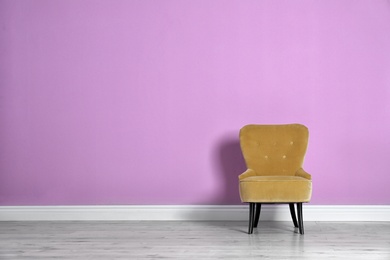 Stylish comfortable armchair against color wall. Modern interior design