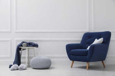 Stylish room interior with pouf and armchair. Space for text