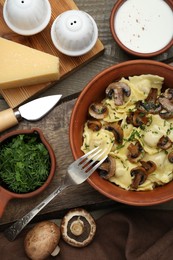 Delicious ravioli with mushrooms and ingredients on wooden table, flat lay