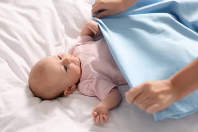 Photo of Mother with her cute little baby on white sheets