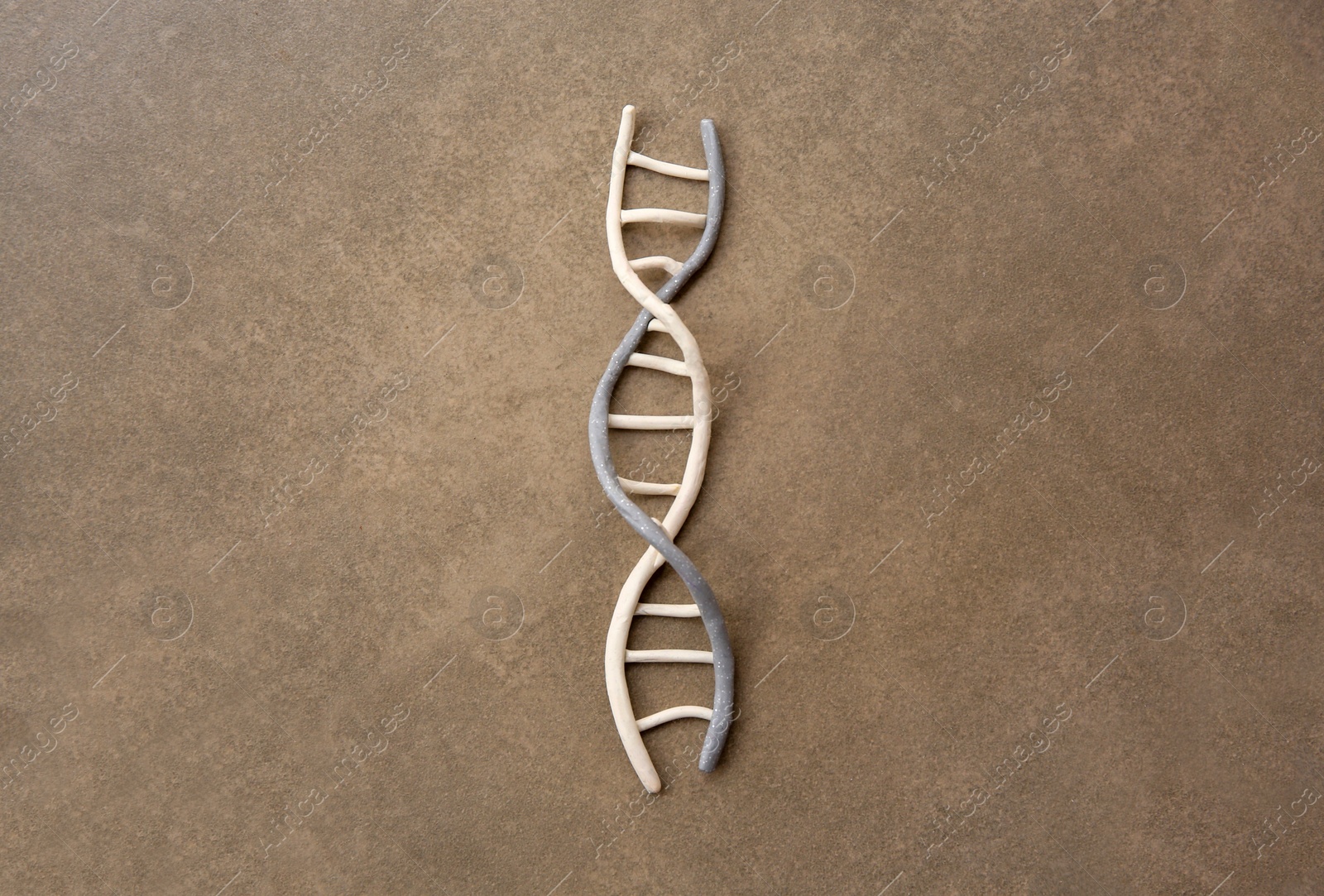 Photo of DNA molecule model made of colorful plasticine on brown background, top view