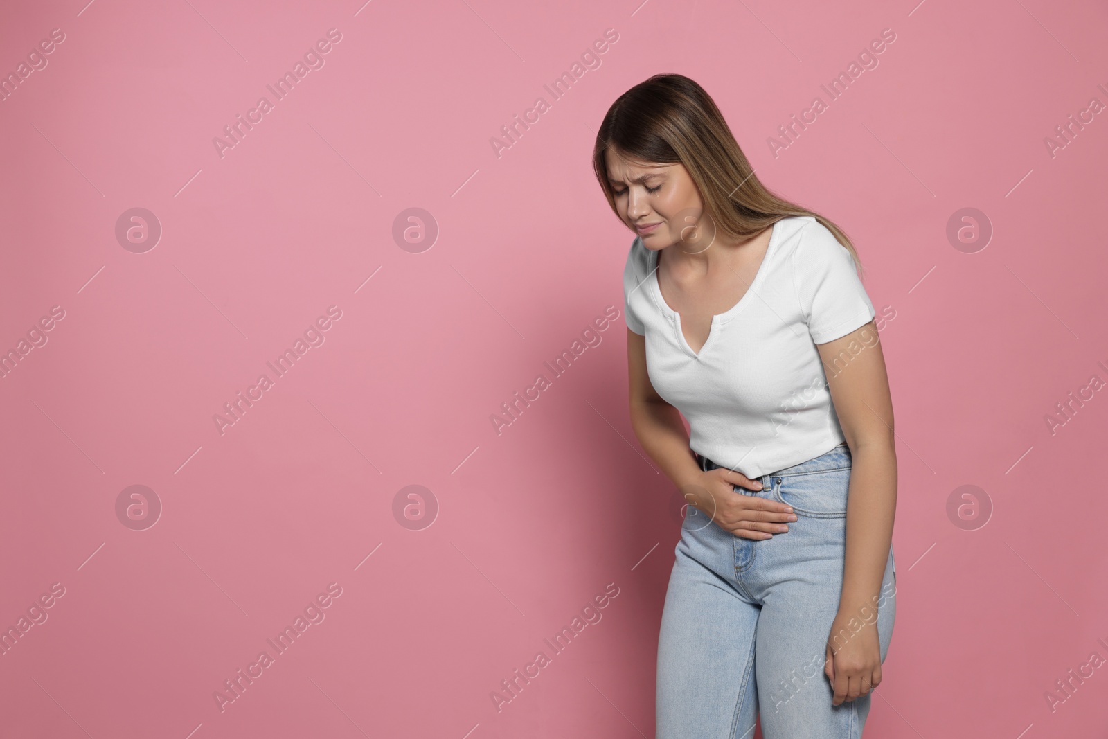 Photo of Young woman suffering from menstrual pain on pink background, space for text