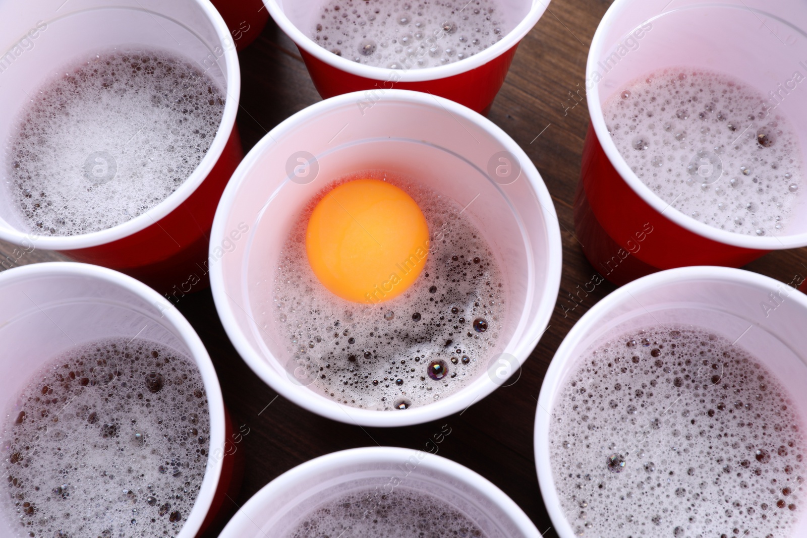 Photo of Plastic cups and ball for beer pong on wooden table, flat lay