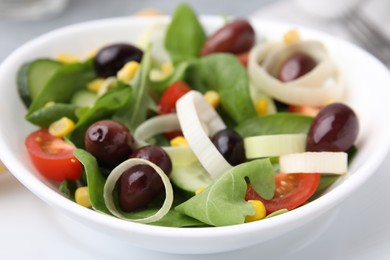 Bowl of tasty salad with leek and olives on table, closeup