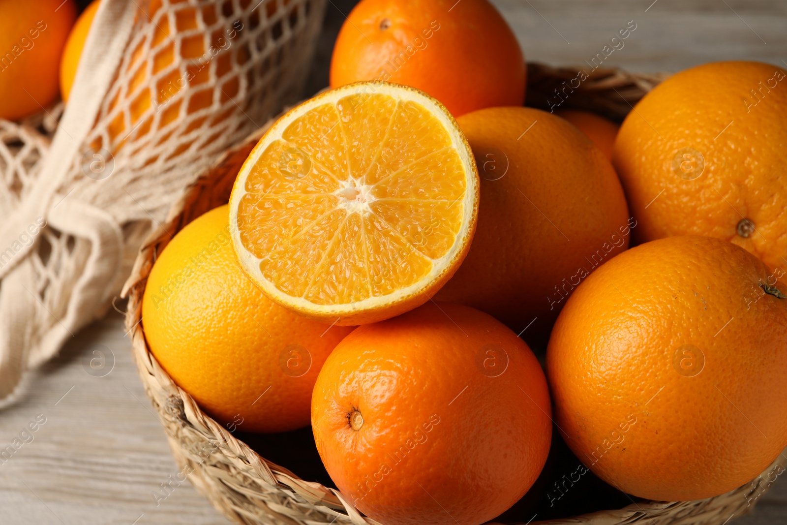 Photo of Many whole and cut oranges on wooden table, closeup