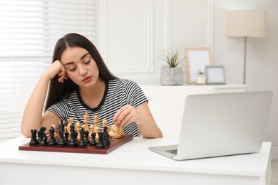 Photo of Unhappy young woman playing chess with partner through online video chat at home