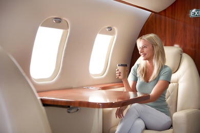 Beautiful woman with paper cup on plane. Air travel