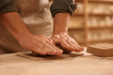 Man crafting with clay at table indoors, closeup