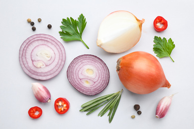 Flat lay composition with cut onion and spices on light background