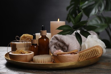 Photo of Spa composition. Brushes, bottles and sea salt on grey textured table, closeup