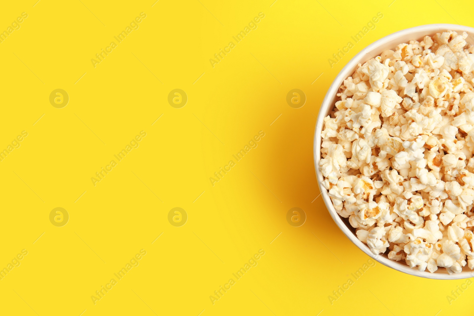 Photo of Tasty pop corn on yellow background, top view. Space for text