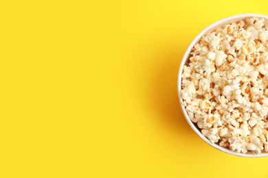 Photo of Tasty pop corn on yellow background, top view. Space for text