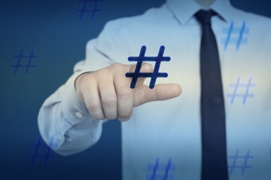 Image of Hashtag concept. Man pointing at sign on blue background, closeup