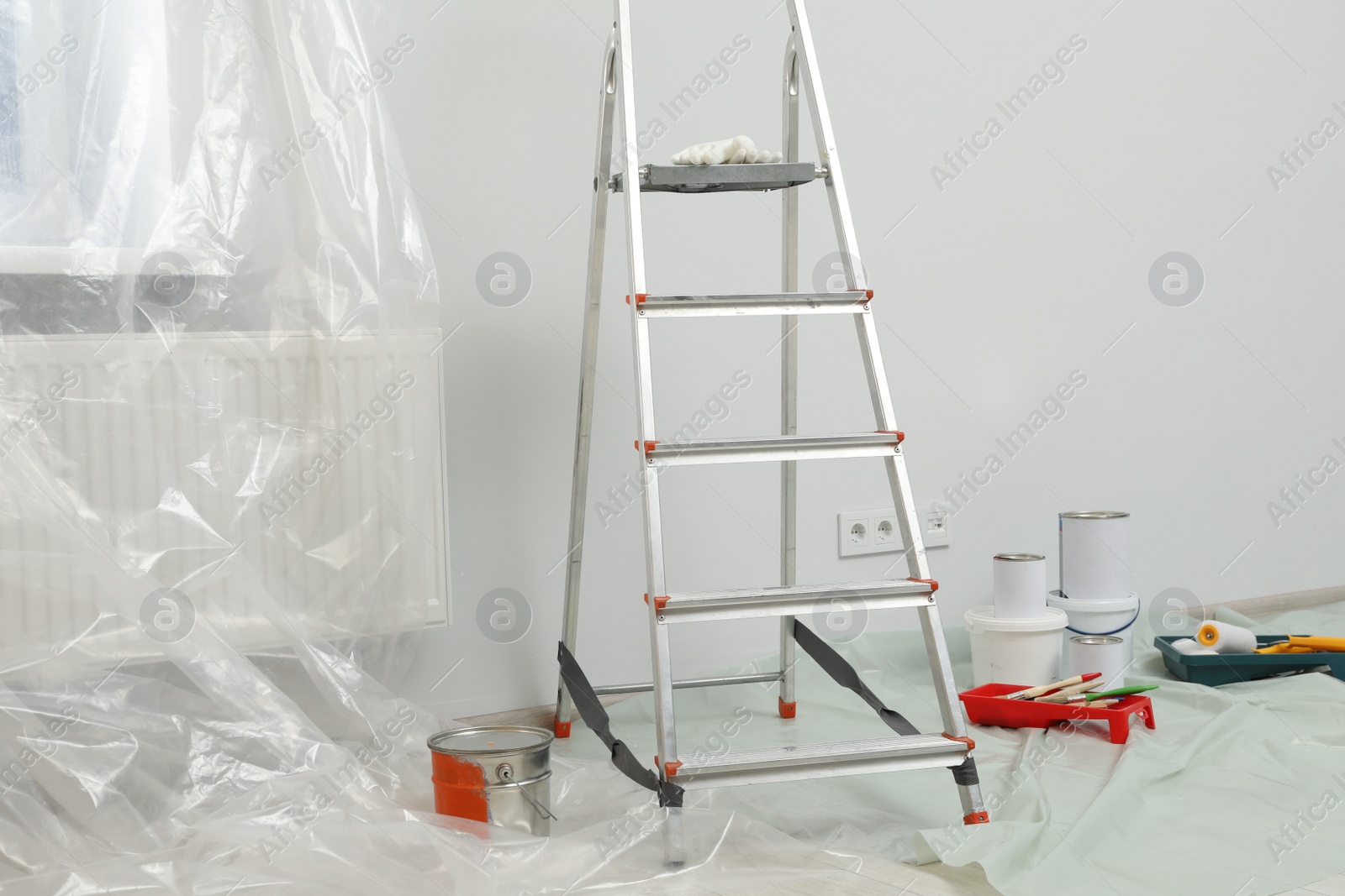 Photo of Metallic folding ladder and painting tools indoors