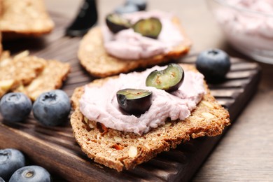 Photo of Tasty sandwiches with cream cheese and blueberries on wooden table, closeup
