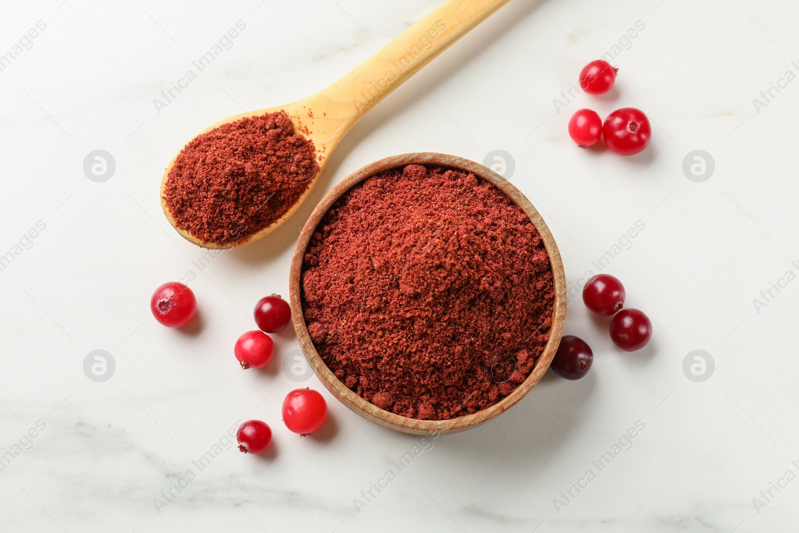 Photo of Dried cranberry powder and fresh berries on white marble table, flat lay