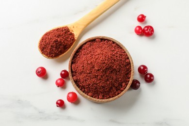 Photo of Dried cranberry powder and fresh berries on white marble table, flat lay