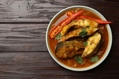 Tasty fish curry on wooden table, top view. Space for text. Indian cuisine