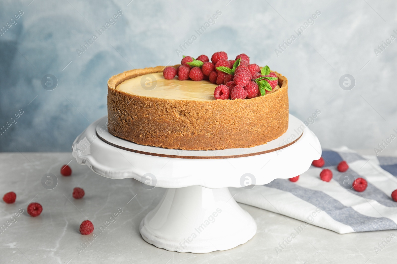 Photo of Dessert stand with delicious raspberry cake on table against blue background