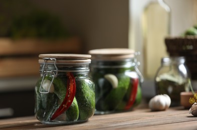 Jar of pickled cucumbers on wooden table. Space for text